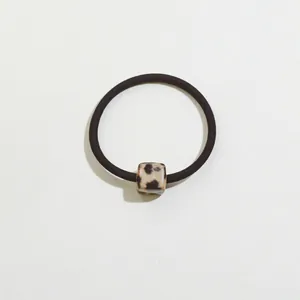Close-up of leopard print cube charm on a high-elasticity black hair tie for women