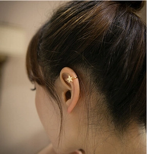 Detailed view of a gold star-shaped ear cuff worn on the upper ear cartilage area