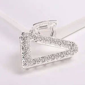 Close-up of silver triangle hair claw with textured metallic finish and glittery surface