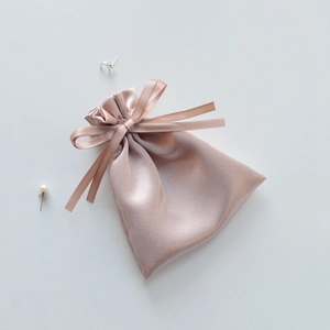 Close-up of pink satin drawstring jewelry pouch with elegant silk ribbon bow detail