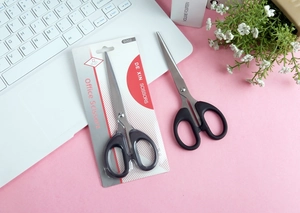 Detail of stainless steel office scissors with black handles and retail blister packaging