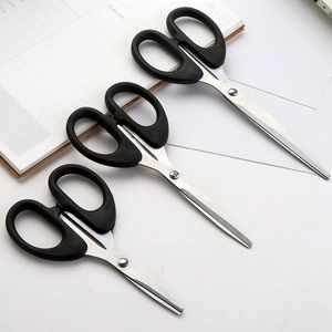 Three-piece black stainless steel scissors set for home and office use on a notebook