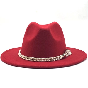 Détail d'un chapeau fedora rouge en laine avec cordelette dorée et accessoire chaîne
