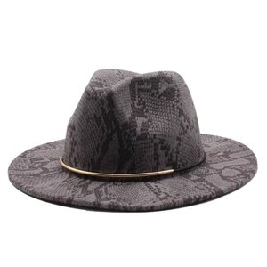 Close-up of wide brim fedora hat featuring black snake skin print and gold metal band