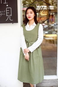 Detail of green cotton apron dress with side pockets and adjustable waist ties
