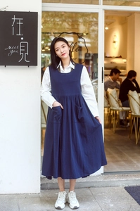Detail of navy blue cotton apron dress with side pockets and stylish layered design