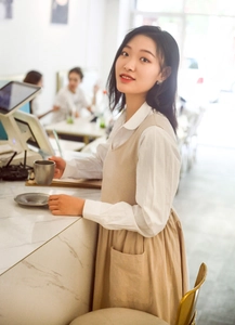 Beige cotton oversized apron worn by a female barista in a cozy cafe setting