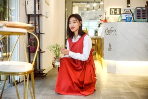 Detail of red cotton apron dress with side bow ties and white long sleeve shirt