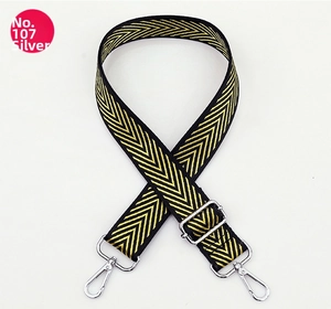 Macro detail of black and gold chevron patterned wide strap with silver metal swivel hooks