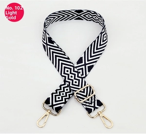 Close-up of black and white geometric woven strap with light gold swivel snap hooks