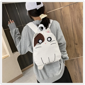 White canvas backpack with cat ears and cartoon face shown on model back view
