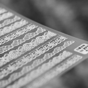 Macro detail of white lace nail art stickers with delicate patterns for DIY manicure