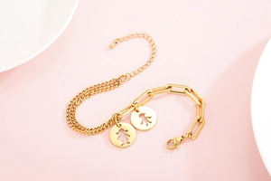 Macro dettagliata del bracciale a doppia catena dorata con ciondoli bimbo e bimba