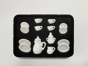 Overhead view of 15-piece white ceramic miniature tea set inside protective black foam packaging