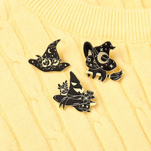 Close-up of three Halloween cat and wizard hat enamel pins on yellow knit sweater