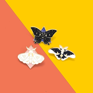 Detailed view of three celestial butterfly enamel pins with moon and star patterns