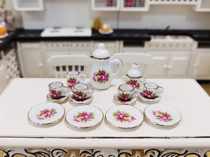 Macro detail of a 15-piece miniature ceramic dollhouse tea set with pink rose patterns