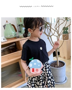 Detail view of a pink mushroom shaped children crossbody bag worn by a young model
