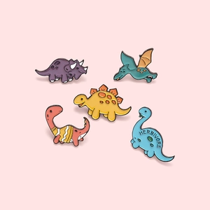 Set of five colorful cartoon dinosaur enamel pins made of zinc alloy on pink background