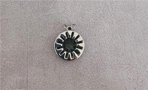 Macro view of industrial style silver compass pendant with embossed sun rays and star