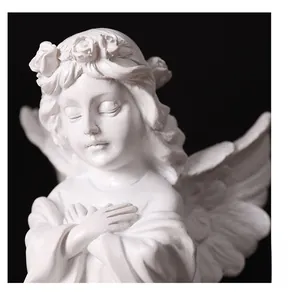 Detailed view of white praying angel statue with floral wreath and feathered wings
