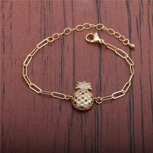 Adjustable golden paperclip bracelet with colorful zircon pineapple pendant on wood background
