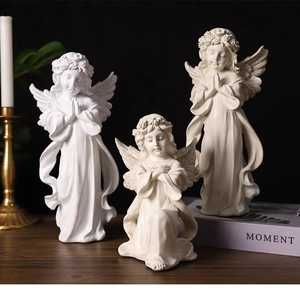 Three Nordic resin angel statues in prayer poses on wooden table with warm lighting