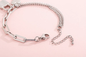 Close-up of silver paperclip chain bracelet with lobster clasp and heart lock detail