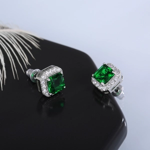 Macro shot of square emerald-cut green zircon earrings with white diamond halo detail