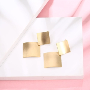 Minimalist geometric gold rhombus earrings with brushed matte finish on pink silk backdrop