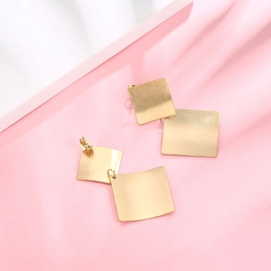 Minimalist double-layered square earrings in brushed gold finish on a soft silk background