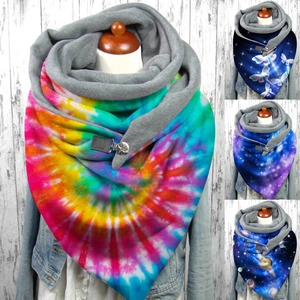 Rainbow tie-dye plush scarf with metal button on denim jacket against white wood background