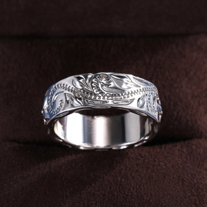 Macro shot of silver wide band ring featuring intricate vintage scroll leaf engraving