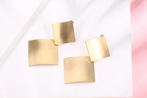 Detail of matte gold geometric rhombus earrings with brushed metal finish for women