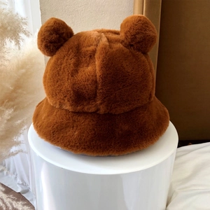 Detail shot of plush brown bear ear bucket hat on a white stand with natural decor