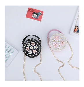 Detail of tweed girl's round crossbody bag with 3D flower and golden chain strap