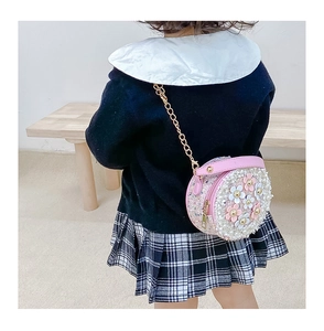 Detail of pink round child purse with 3D flower petals and gold chain strap on model