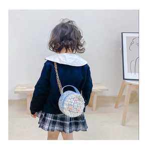 Detail of light blue girls' round crossbody bag featuring floral 3D decor and gold chain
