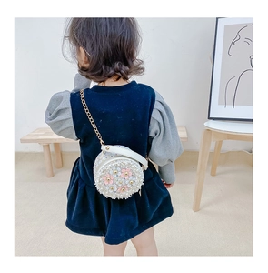 Detailed back view of a girl wearing a pearl-decorated round crossbody bag with 3D flowers
