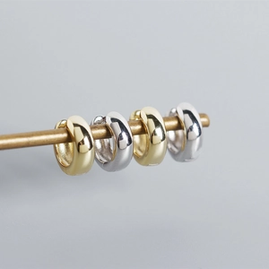 Detailed view of 925 sterling silver huggie hoop earrings in polished gold and silver