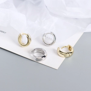 Macro shot of minimalist gold and silver S925 sterling silver hoop earrings on paper