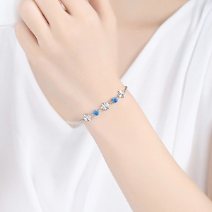 Elegant S925 silver four-leaf clover bracelet with blue gemstones on a female wrist
