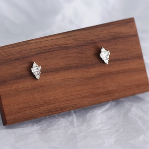 Macro shot of silver geometric earrings with sparkling square crystals on wood