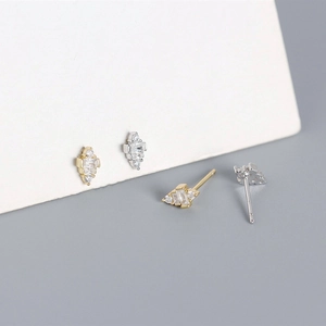 Macro detail of silver and gold S925 stud earrings featuring square-cut sparkling cubic zirconia