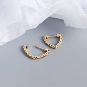 Close-up of golden S925 sterling silver heart earrings with beaded edge detail