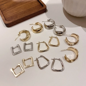 Flat lay of geometric gold and silver plated earrings in diverse minimalist shapes