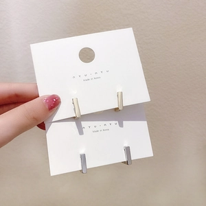 Detail of minimalist rectangular gold and silver stud earrings on display cards