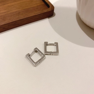 Macro detail of silver geometric square earrings with polished metallic finish and smooth edges