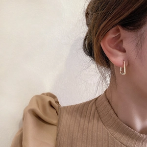 Close-up of golden geometric U-shaped earrings on model for a minimalist fashion look