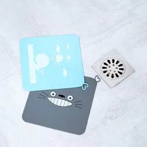 Detail of square silicone floor drain covers with gray Totoro and blue whale patterns